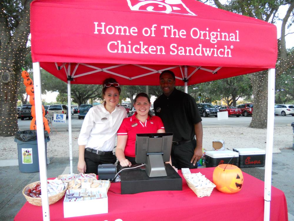 Two women and a man working the Chick-Fil-A food vendor booth